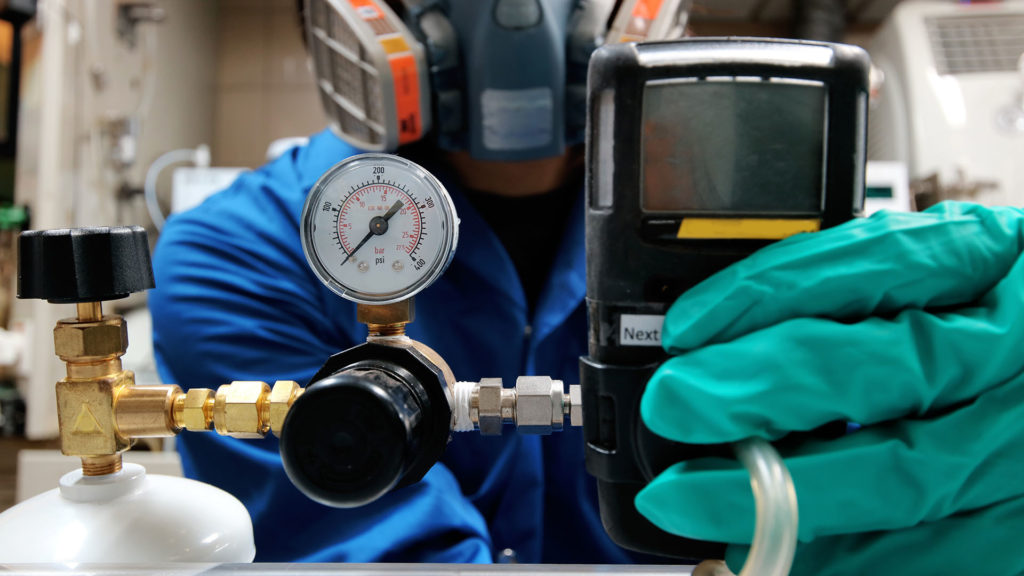 a man in a blue jacket is working on a pipe