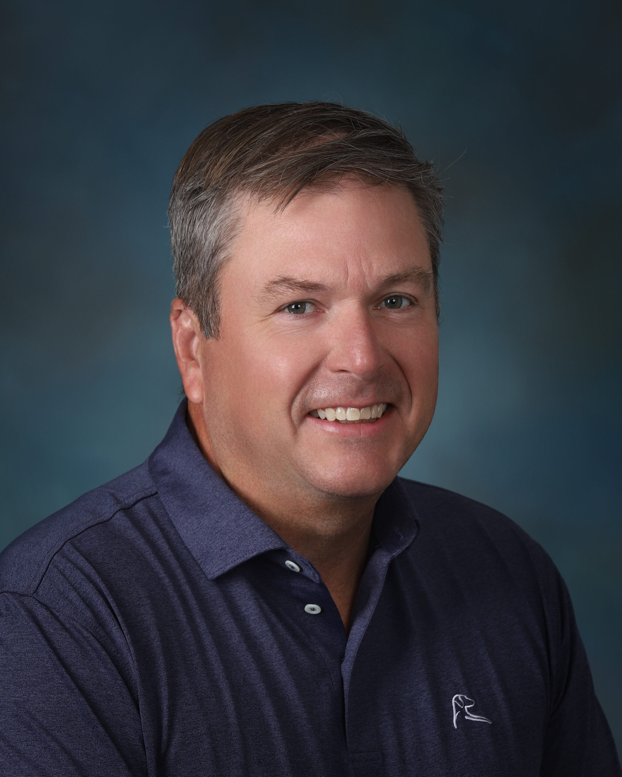 a man in a blue shirt smiling for a picture
