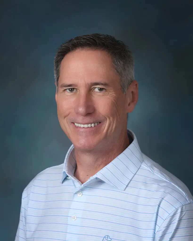 a man in a blue shirt smiling for a picture